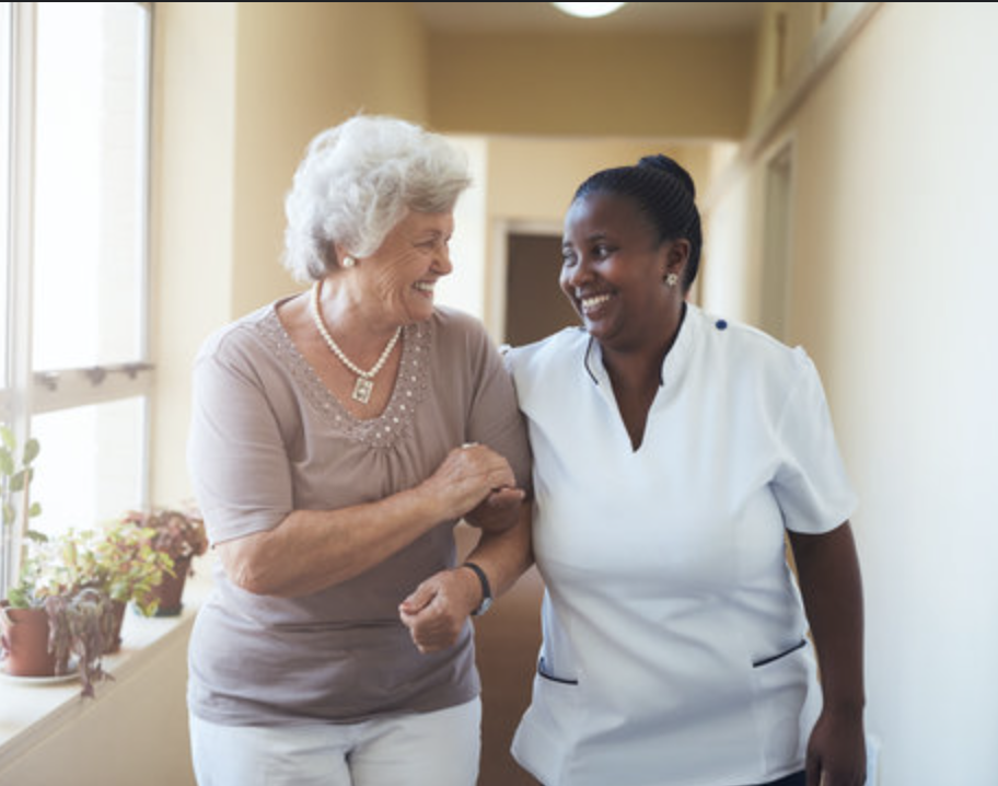 Caregiver embracing elderly woman in wheelchair, both smiling