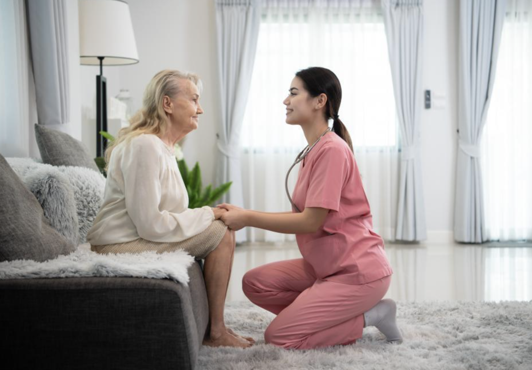Caregiver serving tea to two elderly women in a cozy lounge